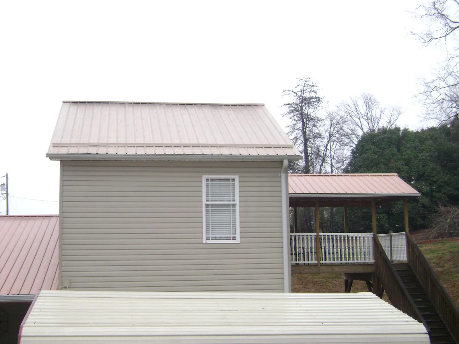 Tan metal roofs on a two story addition and attached porch, from a Roof Replacement job in Lebanon